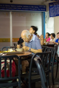 Chinese man eats food at table alone in restaurant.