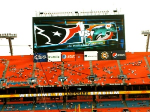 Houston Texans and Miami Dolphins helmets on display in a football stadium.