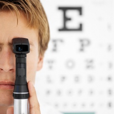 Boy testing eye sight in front of eye chart.