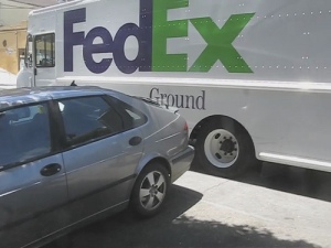 FedEx Ground truck in front of a parked car.