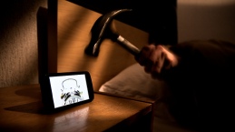 Picture of digital alarm clock and person lying in bed ready to hit alarm clock with a hammer.