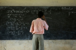 Man writes man formulas on a chalkboard.